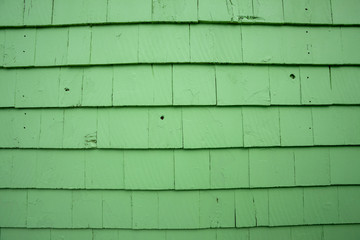 Green wall constructed with shingle siding. Background.