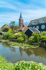 Fototapeta na wymiar Marken, North Holland / Netherlands - June 23rd, 2019: Skyline of the old town with the church in the background and the canal in the foreground