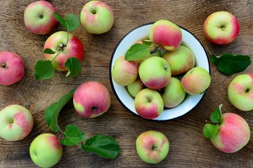 Bright red and green apples in a bowl on a wooden table top view.