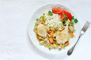keto dish. Chicken with Cauliflower Rice. low carbohydrates a lot of protein. stewed chicken with celery and carrots. in a white plate on a background of a light tablecloth. top view. copy space.