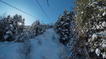 Riding ski chair lift through snowy forest