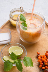 fresh vegetarian fruit smoothie on wooden tray with fresh  bananas, sea buckthorn, lime, melissa and coconut milk . Healthy breakfast. close up