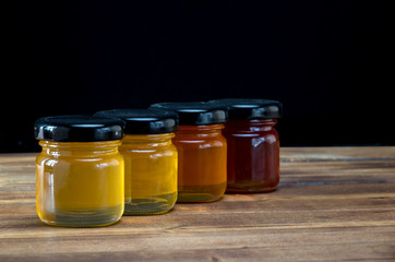 Little jars with honey different colours on wooden table. Selective focus.