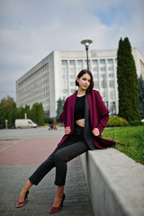 Fototapeta premium A tall leggy young beautiful and elegant model woman at claret coat.