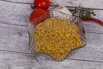Raw bulgur in the bowl with tomatoes and garlic