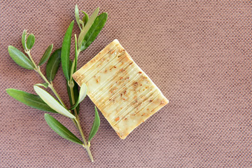 Handmade soap bars and olive branches on fabric background. Top view