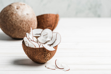 Coconut chips in a brown bowl on a white wooden background