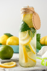refreshing drink lemonade with lemons, mint leaves, lime in a glass bottle