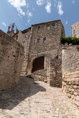 Fototapeta na wymiar Paved street rising with a medieval arch Lacoste in France
