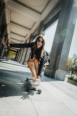 Beautiful young skater woman riding on her longboard in the city. Stylish girl in street clothes rides on a longboard. Skateboard, street photo, life style, freedom, happy face concept. © Aliaksandr Barouski