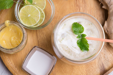 fresh vegetarian banana - ginger cocktail on wooden tray with fresh  bananas,  lime, melissa and coconut milk  . close up. flat lay