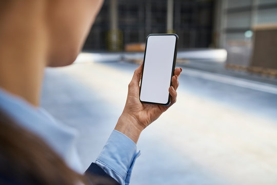 Close-up of businesswoman holding cell phone in factory