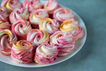 Beautiful bright multi-colored homemade marshmallow in the form of roses on a white plate.