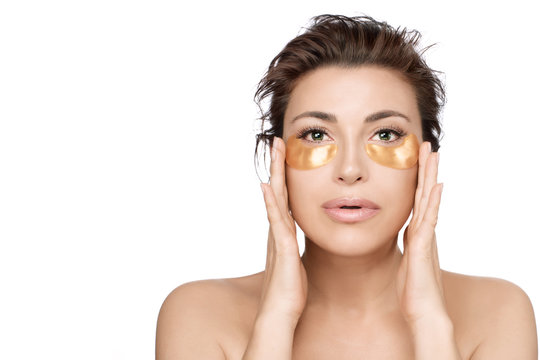 Woman using collagen eye patches to prevent skin aging. Golden hydrogel eye mask