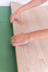 Installation laminate or parquet in the room, worker installing wooden laminate flooring, environmentally friendly soundproofing sheets