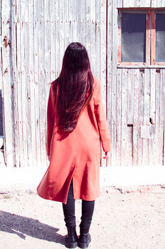 Long Haired Woman Wears Trench Coat While Standing On Her Back On An Old Wooden Background