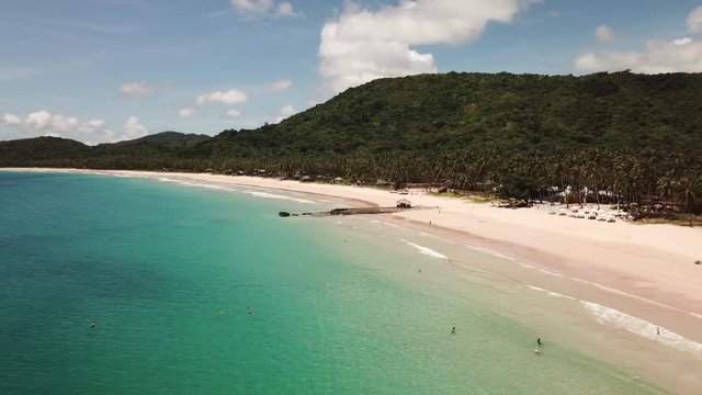 Drone flight along the Twin Beach, Philippines. In the background, view of tropical palm trees on a sunny day. 4K Aerial Shot