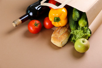 Bunch of mixed organic fruits, vegetables & greens, gourmet pile in full eco friendly shopping bag to reduce ecological footprint. Zero waste concept. Brown table background, copy space, close up.