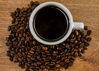 cup of coffee and a pile of coffee beans on a wooden background. Close-up.
