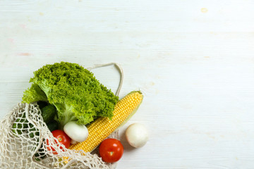 Bunch of mixed organic fruits, vegetables & greens, gourmet pile in full eco friendly shopping bag to reduce ecological footprint. Zero waste concept. White table background, copy space, close up.