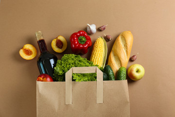 Bunch of mixed organic fruits, vegetables & greens, gourmet pile in full eco friendly shopping bag to reduce ecological footprint. Zero waste concept. Brown table background, copy space, close up.