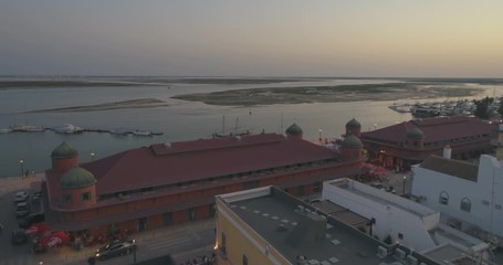Aerial sunset cityscape of Olhao downtown, view of ancient neighbourhoods traditional cubist architecture and landmark market. Algarve, Portugal.