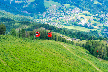 View of St.Gilgen village and colorful Seilbahn cable car gondolas against mountains in Salzkammergut region from Zwolferhorn mountain, Austria © beataaldridge