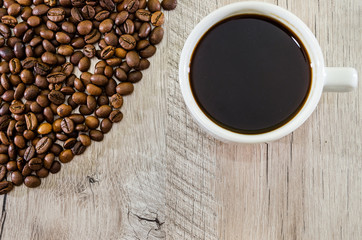 cup of coffee and a pile of coffee beans on a wooden background. Close-up.
