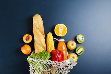 Bunch of mixed organic fruits, vegetables & greens, gourmet pile in full eco friendly shopping bag to reduce ecological footprint. Zero waste concept. Graphite table background, copy space, close up.