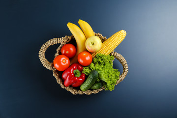 Bunch of mixed organic fruits, vegetables & greens, gourmet pile in full eco friendly shopping bag to reduce ecological footprint. Zero waste concept. Graphite table background, copy space, close up.