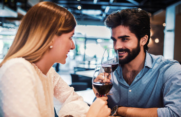 Dating in the cafe. Beautiful couple drinking wine and enjoying in conversation. Dating, love, relationships