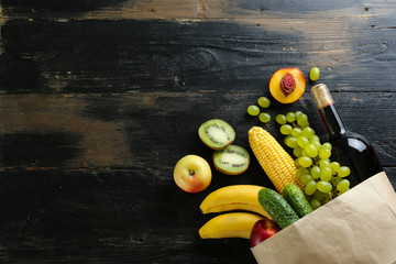 Bunch of mixed organic fruits, vegetables & greens, gourmet pile in full eco friendly shopping bag to reduce ecological footprint. Zero waste concept. Wood table background, copy space, close up.