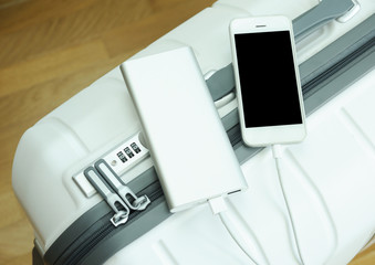Charging a mobile phone with power bank on a white suitcase