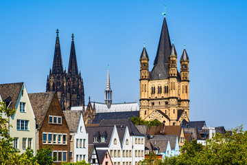 Fototapeta na wymiar Skyline of the old town with solorful houses rooftops, the tower of the Cologne gothic cathedral and the tower of Gtreat St. Martin church in Cologne, North Rhine Westphalia, Germany