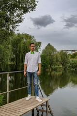 young man with a green bow-tie on a bridge on a lake background