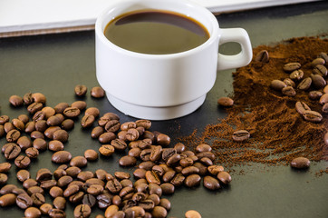 cup of coffee, ground coffee and coffee beans on a black background.