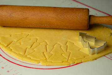 Raw dough for Christmas cookies and cookie cutters shaped Christmas tree
