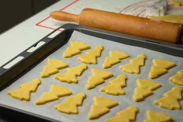 Raw dough for Christmas cookies and cookie cutters shaped Christmas tree