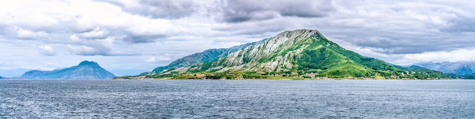 Panorama of clouds above Angarsnesvika marina, fjord and mountains. Tides out but green and brown seagrass remains on the coast of Alsta Island. Close to Sandnessoen town, Norway