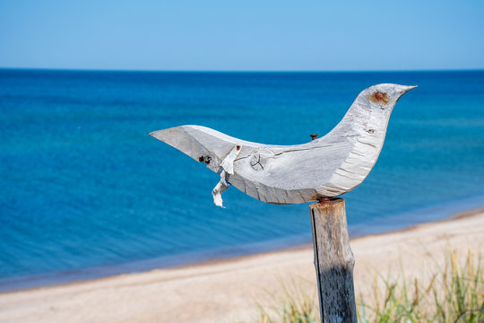 Wooden sculpture of a seagull with blue sea and sandy beach in the background