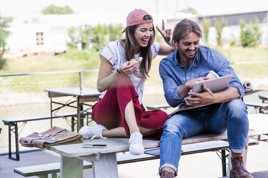 Young couple sitting on table in a beer garden using tablet