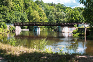 Wooden bridge over the river Vilia in Vilnius with a waterfall in the park Belmonto.