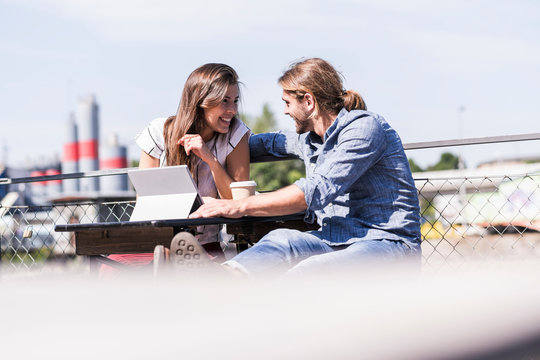 Happy young couple with tablet in a beer garden