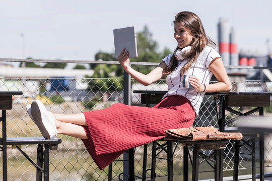 Young woman relaxing in a beer garden using tablet