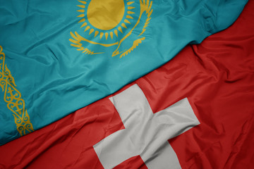 waving colorful flag of switzerland and national flag of kazakhstan.