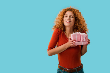 happy curly girl holding gifts isolated on blue