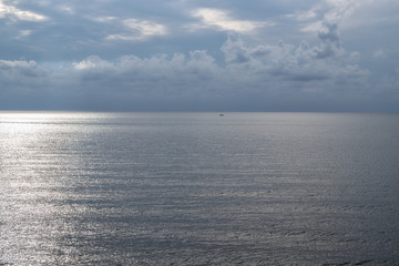 Obraz premium In the distance, a lonely sailboat on a calm sea, natural evening light
