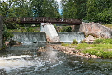 Obraz premium Wooden bridge over the river Vilia in Vilnius with a waterfall in the park Belmonto.
