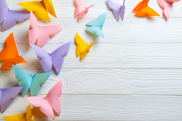 White wooden background with a bunch of colorful paper origami butterflies with copy space for your...