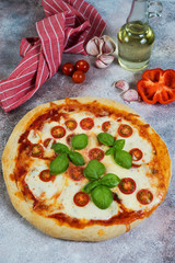 Pizza Margarita with tomatoes and mozzarella cheese on a concrete background. Horizontal photo with copy space